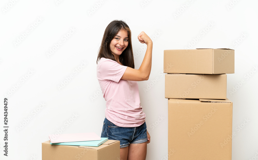 Young girl moving in new home among boxes making strong gesture Young girl moving in new home among boxes making strong gesture