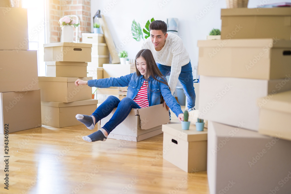 Funny asian couple having fun, riding inside cardboard box smiling happy, very excited moving to a new house Funny asian couple having fun, riding inside cardboard box smiling happy, very excited moving to a new house
