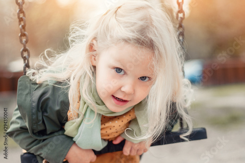 Closeup portrait of a little blonde happy girl in the outdoors. Happy childhood concept. Emotion, smile and childish mischief.