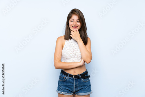 Young woman over isolated blue background looking to the side