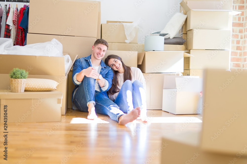 Young beautiful couple relaxing sitting on the floor around cardboard boxes at home, smiling happy moving to a new house Young beautiful couple relaxing sitting on the floor around cardboard boxes at home, smiling happy moving to a new house