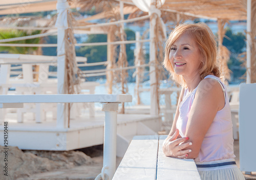 Mature Woman Relaxing in the outdoor, on the beach by the sea. Happy mature woman of 65 years on the beach.