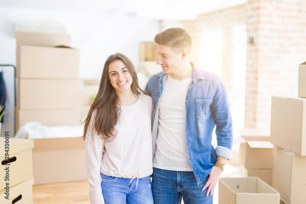 Beautiful young couple moving to a new home, standing on new aparment around cardboard boxes, hugging smiling happy and in love Beautiful young couple moving to a new home, standing on new aparment around cardboard boxes, hugging smiling happy and in love