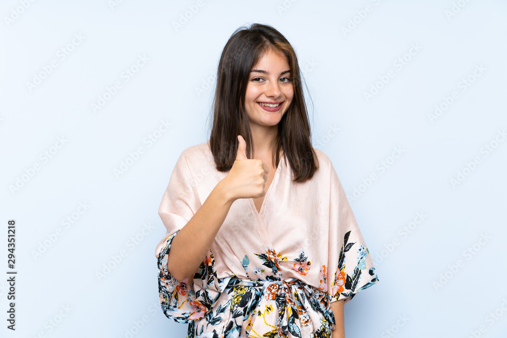 Caucasian girl with kimono over isolated blue background giving a thumbs up gesture Caucasian girl with kimono over isolated blue background giving a thumbs up gesture