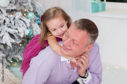 Baby girl laughing dabbles with dad near Christmas tree photo