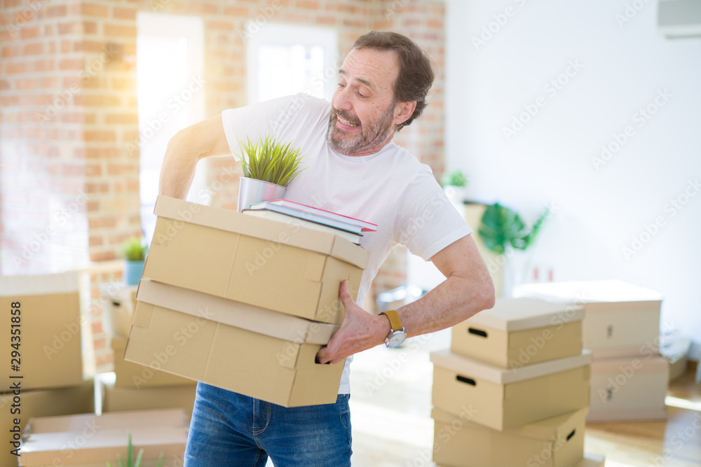Handsome middle age senior nervous man triying to hold cardboard boxes, upset for box falling Handsome middle age senior nervous man triying to hold cardboard boxes, upset for box falling