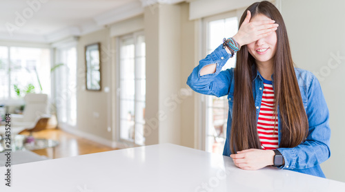 Young beautiful asian woman with long hair wearing denim jacket smiling and laughing with hand on face covering eyes for surprise. Blind concept.