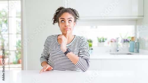 Beautiful african american woman with afro hair wearing casual striped sweater Thinking concentrated about doubt with finger on chin and looking up wondering