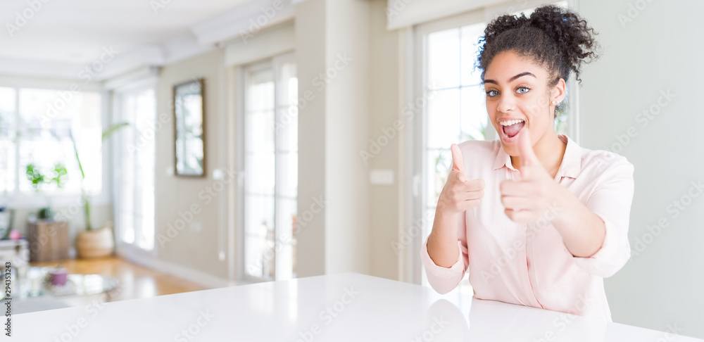 Wide angle of beautiful african american woman with afro hair pointing fingers to camera with happy and funny face. Good energy and vibes.