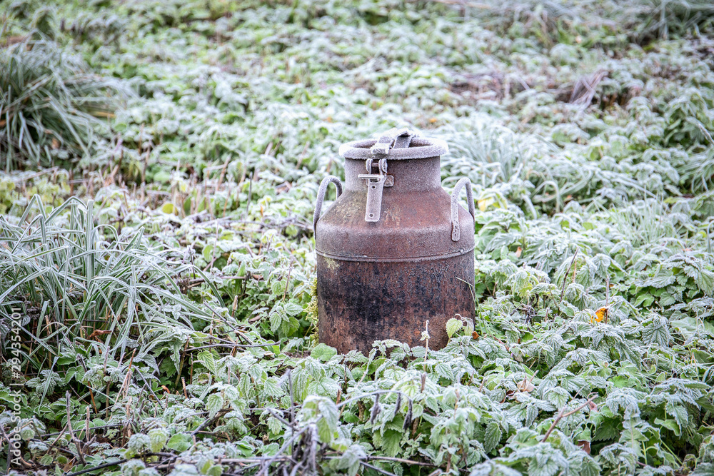 Old milk can in the field covered with frost. Abandoned fields, agriculture and loneliness concept Old milk can in the field covered with frost. Abandoned fields, agriculture and loneliness concept