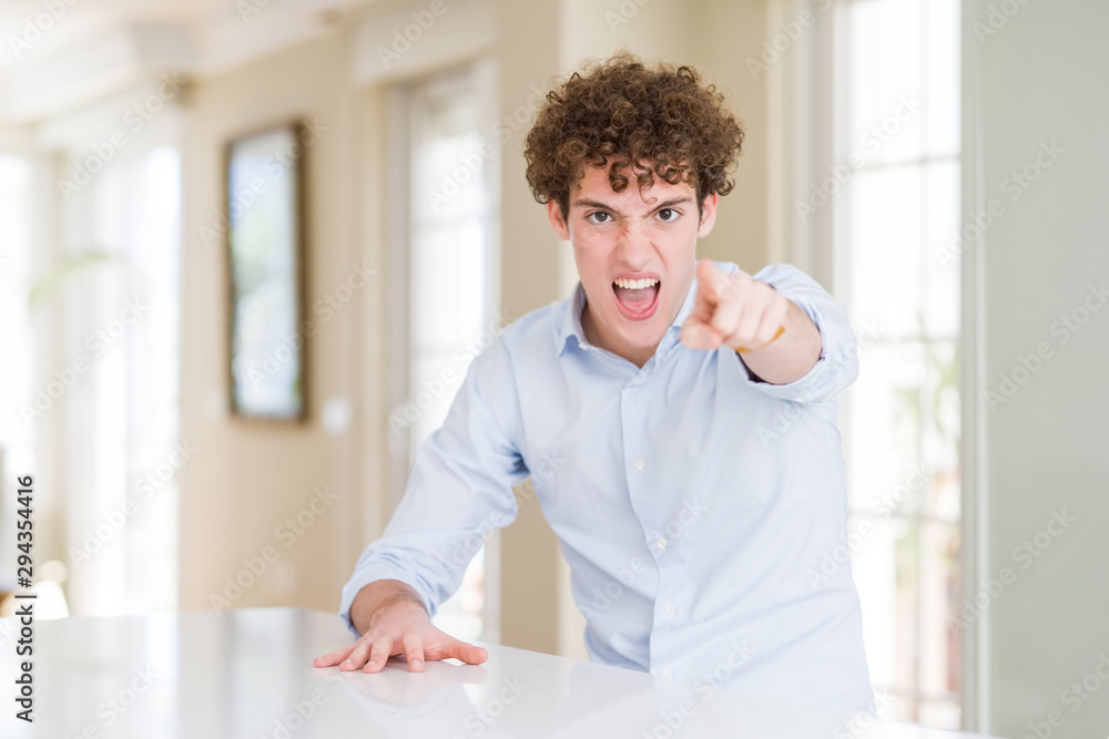 Fototapeta premium Young business man with curly read head pointing displeased and frustrated to the camera, angry and furious with you