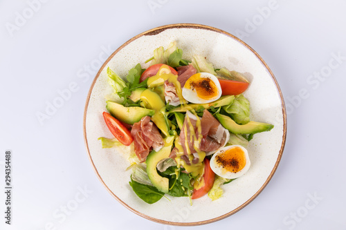Healthy breakfast. Salad with prosciutto, tomato, egg, avocado