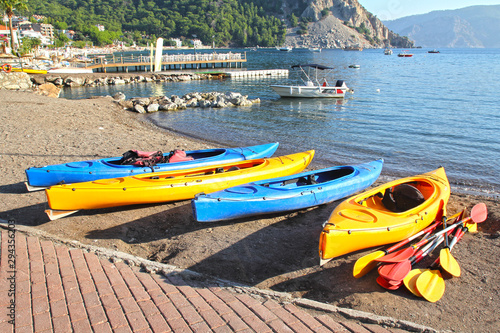 Multi-colored kayaks with oars on the seashore.