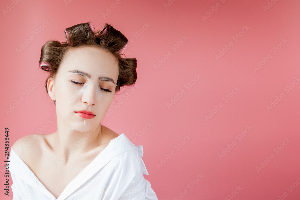 Beautiful young girl with a mask and curlers touching her face. Beautiful young girl with a mask and curlers touching her face.