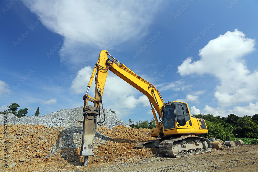 Yellow backhoe working scoop rock dig a large well or Industrial excavator loading soil material from the garden Yellow backhoe working scoop rock dig a large well or Industrial excavator loading soil material from the garden