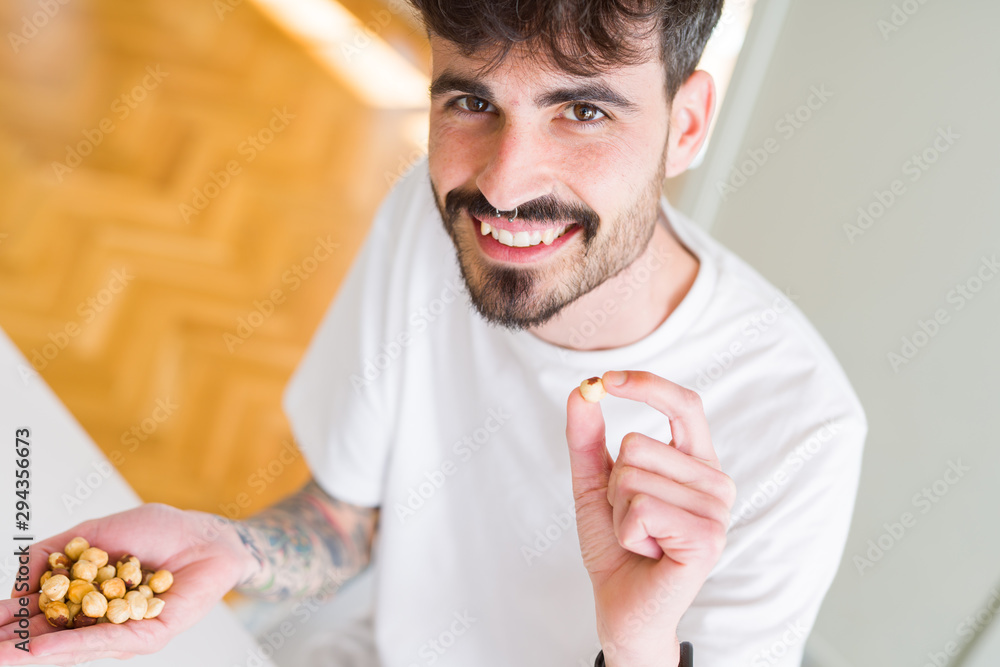Young man eating hazelnuts, close up of hand with a bunch of healthy nuts