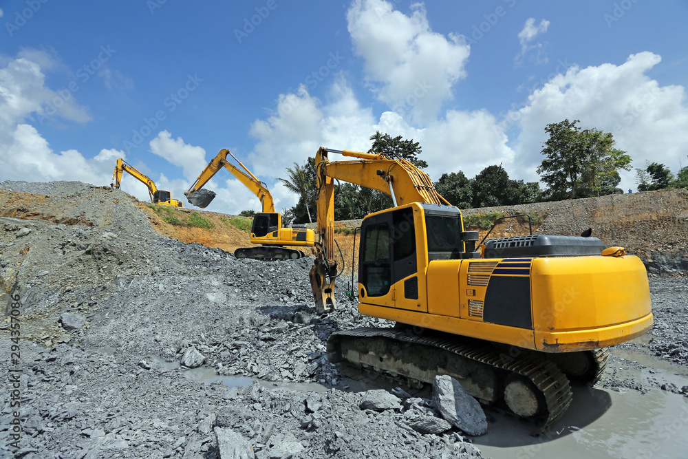 Yellow backhoe working scoop rock dig a large well or Industrial excavator loading soil material from the garden