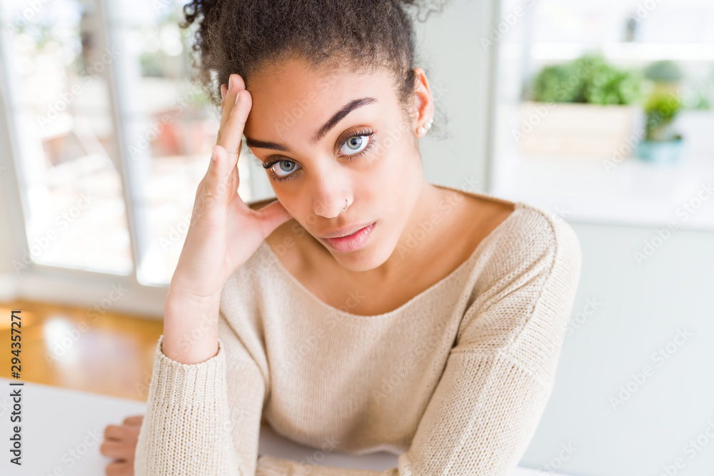 Beautiful young african american woman with blue eyes relaxing at home, with confident expression on face Beautiful young african american woman with blue eyes relaxing at home, with confident expression on face