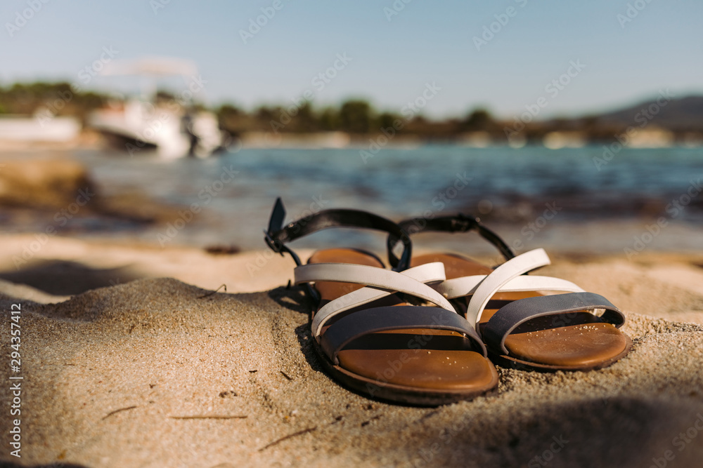 Pair of female sandals on the beach. Pair of female sandals on the beach.