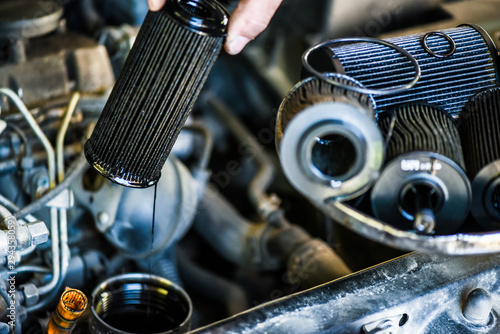 Mechanic changing old or used oil filter from car engine. Vehicle service or maintenance.