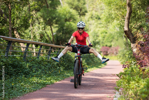 Woman cyclist riding mountain bike outdoors have fun with legs outstretched