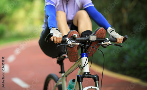 Woman cyclist riding mountain bike outdoors,have fun with legs on handlebar