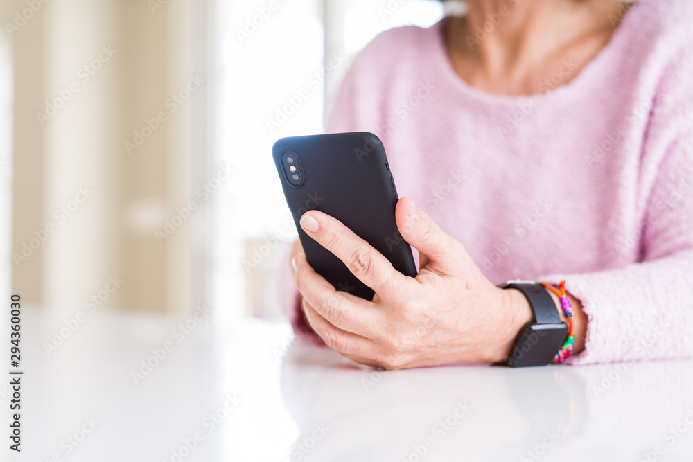 Close up of senior woman using smartphone over white table