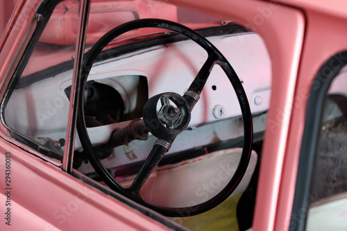 Steering wheel in an old pink car © aquatarkus