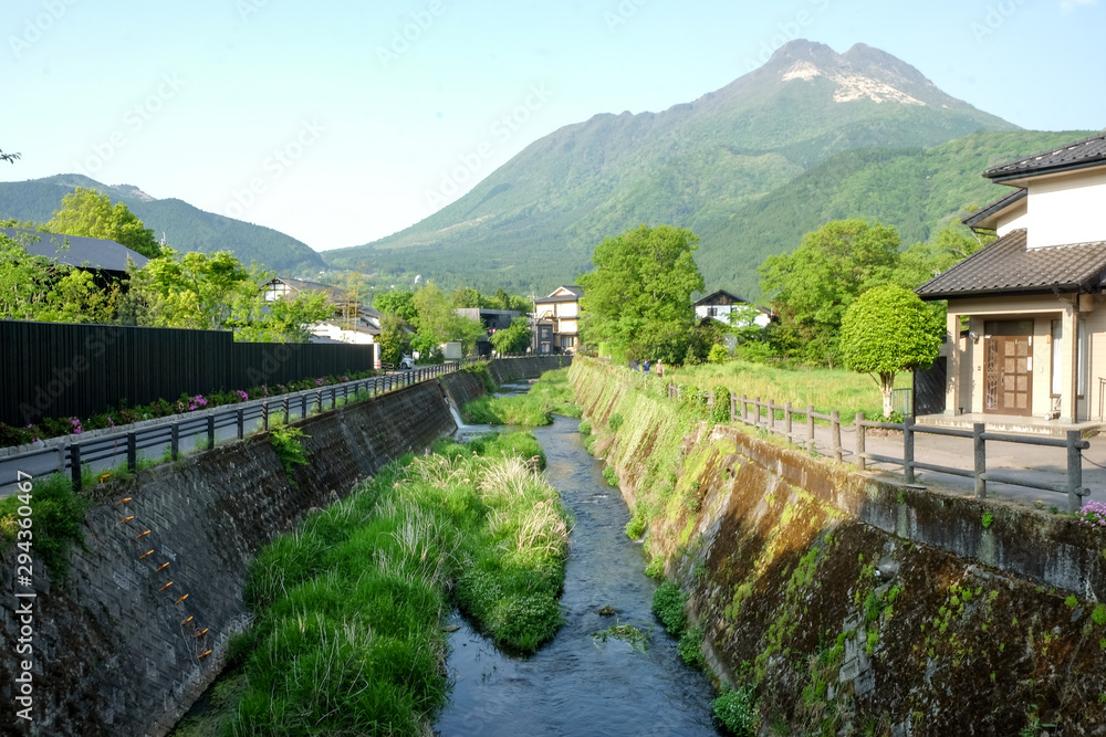 Beautyful View of Oita river flowing through Yufuin city with Mount Yufu in Background and clear sky in summer. onsen town, Yufuin, Oita, Kyushu, Japan Beautyful View of Oita river flowing through Yufuin city with Mount Yufu in Background and clear sky in summer. onsen town, Yufuin, Oita, Kyushu, Japan