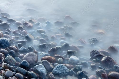 multi-colored smooth stones by the sea at a long exposure in twilight