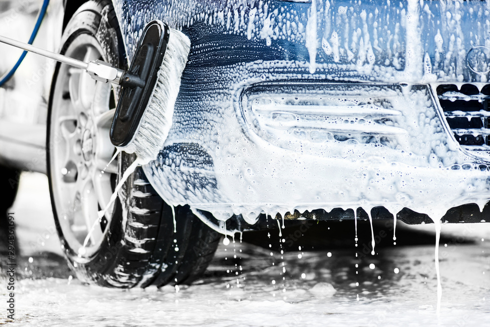 Car cleaning close up. Front bumper clean using foam and brush at car