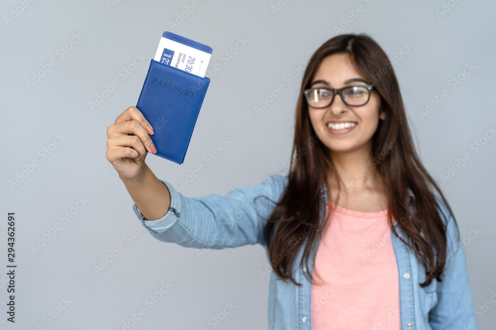 Happy excited young adult Indian woman student holding passport with  airplane flight ticket boarding pass standing isolated on grey background  with copy space, travel by plane, study abroad concept Photos | Adobe