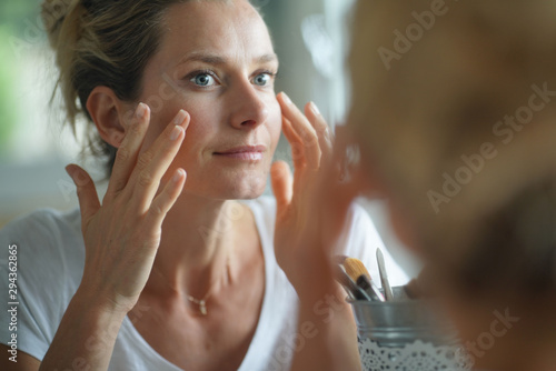 Portrait of woman looking at her face in mirror