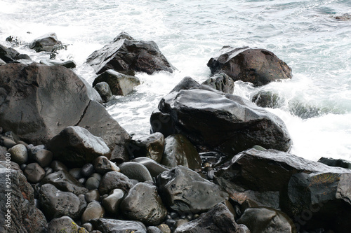 Volcanic stones on ocean shore, cold clean water, waves, Madeira island, Portugal