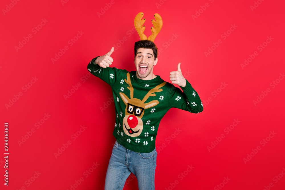 Portrait of his he nice attractive cheerful cheery glad guy wearing deer sweater showing two double thumbup isolated over bright vivid shine vibrant red color background Portrait of his he nice attractive cheerful cheery glad guy wearing deer sweater showing two double thumbup isolated over bright vivid shine vibrant red color background