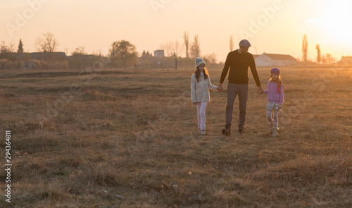 Family, parenthood, fatherhood, adoption and people concept - happy father and little children walking outdoor