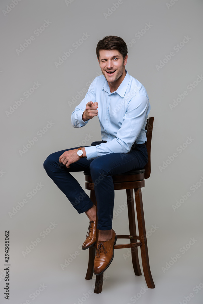 Full length portrait of handsome young businessman sitting on chair Full length portrait of handsome young businessman sitting on chair
