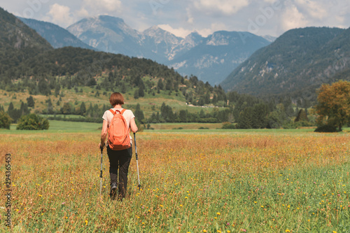 Female hiker is trekking in alpine countryside landscape in autumn