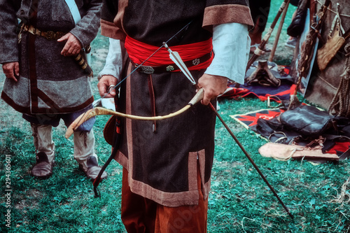 Archer retro tribe stands with a bow in his hand. Reconstruction old life of the nomadic peoples. Bow and arrow for hunting in hand. photo