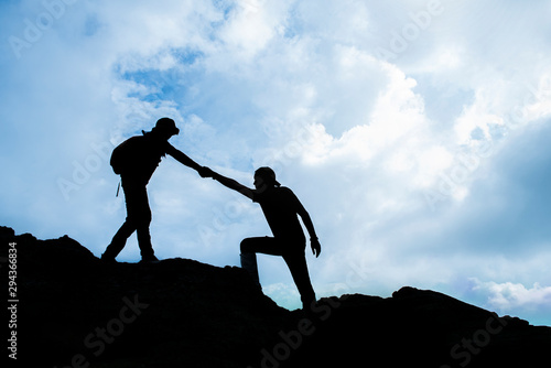 Siluate of Woman helping to pull friend from cliff photo