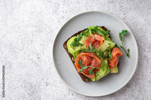 Fototapeta toast with dark rye bread, avocado, smoked salmon and cucumber