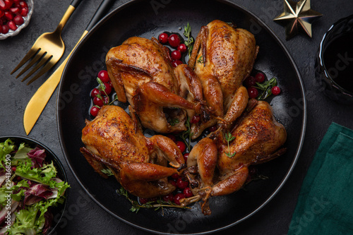 Murais de parede Roasted quail with cranberry and thyme on black plate for Christmas dinner,