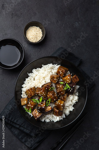 roasted teriyaki eggplant with rice in black bowl, top view