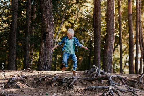 Emotional portrait of a happy and cheerful little boy  running after a friend laughing while playing on a walk in the park. Happy childhood. Summertime. Summer vacation. Positive emotions and energy