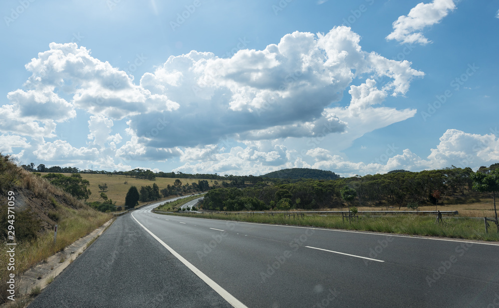 Naklejka premium Rural street with full of green trees in blue sky.