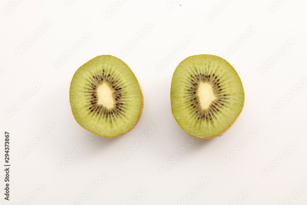 Kiwi cortado en dos sobre fondo blanco, vista cenital. Kiwi cut in two on white background, overhead view. Kiwi cortado en dos sobre fondo blanco, vista cenital. Kiwi cut in two on white background, overhead view.