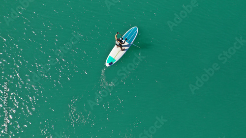 Aerial drone bird's eye view photo of young woman practising paddle board or sup in tropical lake