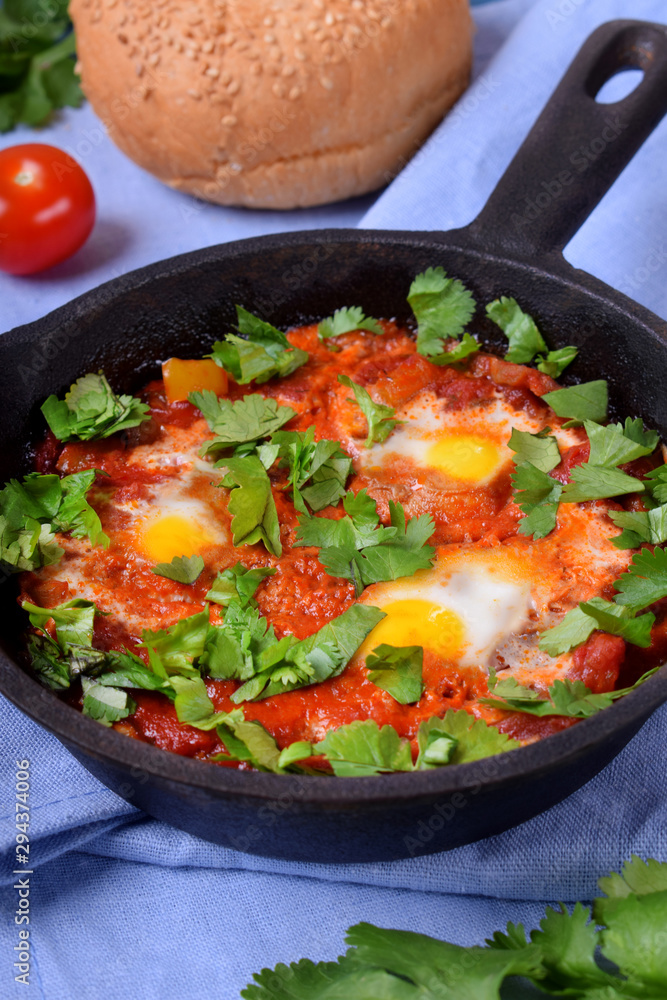 Shakshuka with tomato sauce and quail eggs topped with cilantro in a cast iron pan