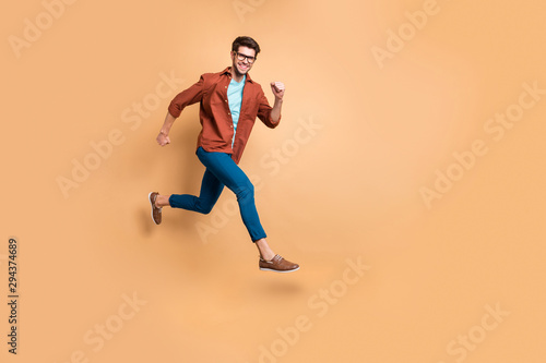 Full length body size view of nice attractive cheerful cheery strong sportive successful guy leader jumping in air running fast hurry-up meeting appointment isolated over beige color pastel background