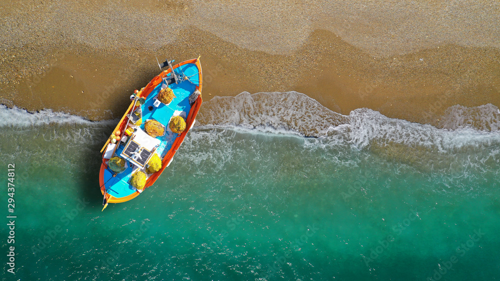Fototapeta premium Aerial top view photo of red traditional wooden fishing boat in Aegean island destination beach with emerald sea